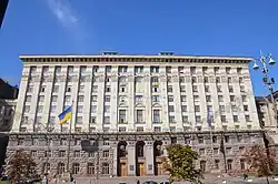 Ten-storey rectangular concrete building with rows of square windows on each side of arched windows in the middle
