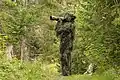 Wildlife photographer wearing a ghillie suit. Winner of the People in Science category 2023, Giles Laurent, Switzerland