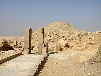 Photograph of a path, two vertical columns and main pyramid.