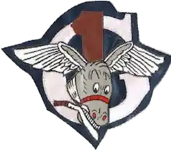 upper case letter gee, white on a blue background, imposed on it is a red number one, imposed on both is the grey head of a smiling mule, with eagle wings spread from each ear and holding a machete in its teeth