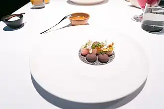 A taco made of ceviche and Mexican pepper leaves accompanied by a few drops of beans.