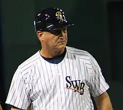A man in a white baseball uniform with dark pinstripes.
