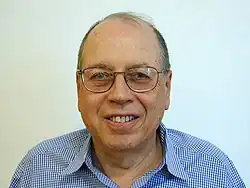 Shoulder high portrait of man in his sixties in a checked shirt with a blank white background
