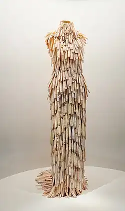 A full-length sleeveless dress with high collar, completely covered in long bleached clamshells