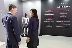 The Fourth Industrial Revolution in the 2020s is referred to as industrial change with emerging technologies such as AI, gene editing, and advanced robotics that blur the lines between the physical, digital, and biological worlds. Automation also continues to take over human jobs. Above is a photo of a Tesla Bot, which Tesla, Inc. hopes to begin selling by 2027.