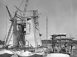 Depiction of a large, concrete and steel structure during its construction.