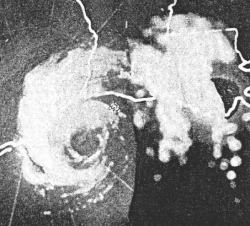 Black and white radar image of a hurricane. Rain is visible as white shapes. The cyclonic circulation of the rains is apparent, and the hurricane has a void of rain near its center, denoting an eye.
