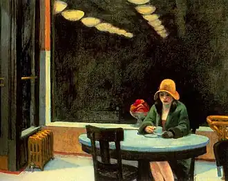 A woman sits alone at a table with a coffee cup in a brightly lit automat
