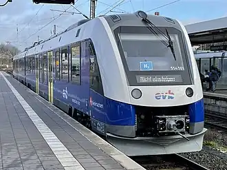 White rail vehicle with blue striping at station platform