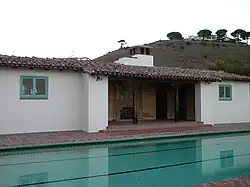 The bathhouse featuring interlocking blue and red tile floors, hand-carved wooden support beams, a wrought-iron gated outdoor fireplace, and a fresco of a Portuguese explorer.