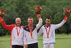 Three men holding bouquets in their hands and Olympic medals around their necks