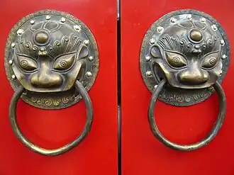 A traditional red Chinese door with Imperial guardian lion knocker resembles the number 8 (good luck or fortune in Chinese culture)
