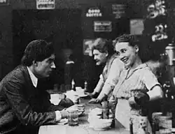 Black and white film still showing a woman serving a customer