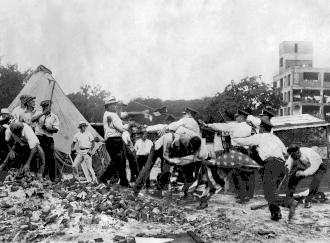 Police with batons confront demonstrators armed with bricks and clubs. A policeman and a demonstrator wrestle over a U.S. flag.