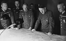 Photograph of Halder standing on Adolf Hitler's left side looking at a map with four other officers