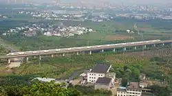 High-speed train crossing a rural landscape of fields on a concrete viaduct