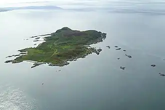 A green island sits in a clam sea. There are numerous small islets in the surrounding waters.