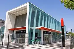 Photo of a modern, glass-panelled light rail station entrance under construction which appears largely complete