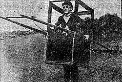 A black-and-white image of a man in a sedan chair, his legs through the bottom