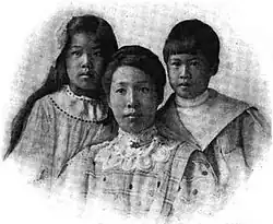 An Asian-American mother and her two children in a formal portrait; the daughter and son are about 11 and 9 years old, respectively; the daughter has long dark hair, the son has dark hair cut short with bangs; the mother's dark hair is in an updo, and she is wearing a high lace collar.