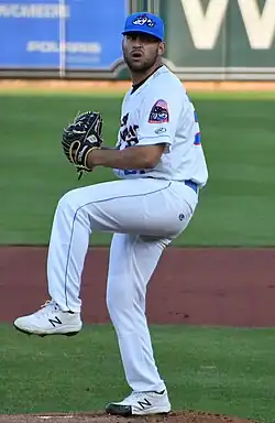A man in a white baseball uniform and blue cap