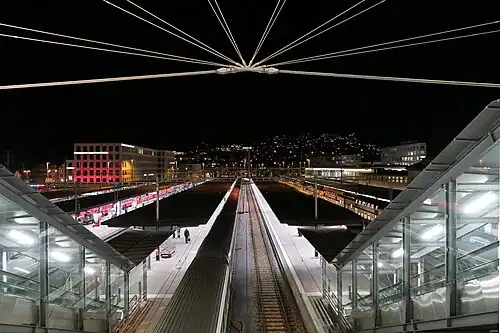 Gravel-topped platform canopies with red trains on the tracks between them