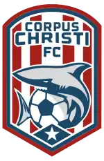 A badge with red and white vertical stripes. A shark surrounding a soccer ball is depicted at the center of the badge.