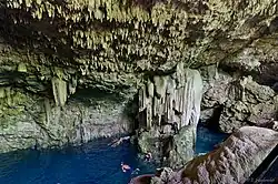 Vista del interior del cenote en donde se ven personas nadando.