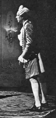 tall, clean shaven white man in white 18th-century wig and 18th-century aristocrat's costume