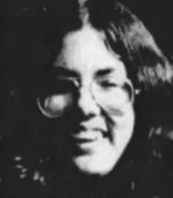 A young white woman, smiling and wearing glasses