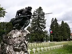 Monument représentant un fantassin français, baïonnette au canon. La statue en bronze est placée au sommet d'un rocher (photographie moderne).