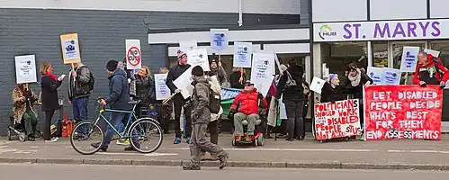 Disabled people protesting in 2015 against government policies and the inaccessibility of the assessment centre which has now been taken over by Maximus Inc. outside St Marys House, Norwich.