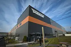 Exterior photo of Dorman Products headquarters in Colmar, Pennsylvania, with the Dorman logo at the top of the building and a contributor walking into the building