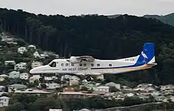 A small plane flies over a wooded, residential area.
