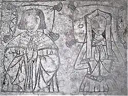 The top of the alabaster tomb. The figures are incised and traces of neillo (a black filling material) remain. They are shown half length: he wears an ermine robe, she a kennel headdress, gown, belt and gloves. The heads of both rest on tasselled pillows.