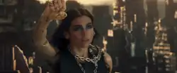 Dua Lipa with raising her cyborg arm with an apocalyptic city behind her