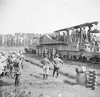 Presentation of a 320&nbsp;mm model 1870/84 cannon on a railway track to a Chinese military mission, in August 1917 in Thierville-sur-Meuse. The gunners operate the jacks lowering the six support crosspieces.
