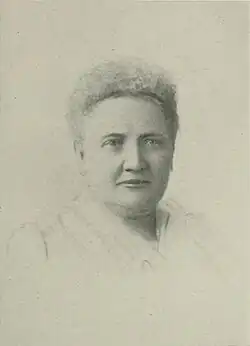 B&W portrait photo of a woman with short white hair wearing a pale blouse.