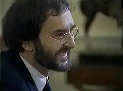 Closely framed headshot of a bearded Morris with glasses, gazing right