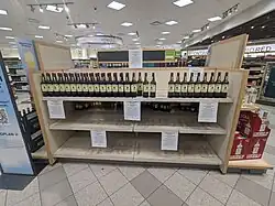 A shelf in a liquor store, it is empty except for the top shelf