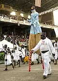 A performer on stilts as part of the Eyo Agere Molokun procession parading in the TBS.