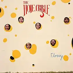 A large cut-out of Swiss cheese with holes that are large enough for the band member's faces to be visible