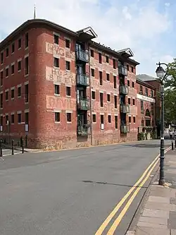 A red brick warehouse on four floors, now converted as flats. The loading doorways were slightly inset into the wall and now have protruding glazed balconies added.