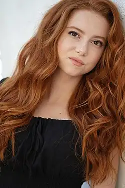 A young woman with red hair smiling.
