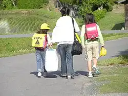 Two sisters wearing pink randoseru. One of them with a yellow plastic cover worn by 1st graders.