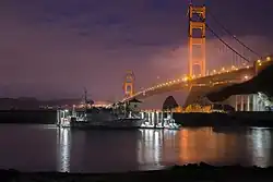 47-foot Motor Lifeboat moored at Coast Guard Station Golden Gate at night. Station Golden Gate is located on the grounds of Fort Baker in Sausalito, California, and the illuminated Golden Gate Bridge is visible in the background.