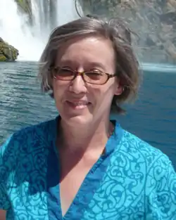 Photograph of Hagelberg in blue shirt with sunglasses in front of waterfall