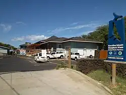 A parking lot with a closed gate in front of one-story buildings