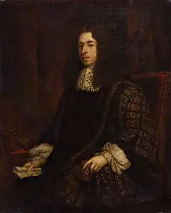 A dour-looking man sitting in a simple, studded, leather chair. He is wearing an ornate black robe with gold trim, and possibly a large brown wig, although that may be his hair. In his hand is a piece of paper.