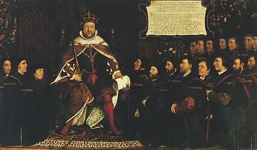 King Henry VIII in full royal regalia surrounded by a kneeling group of men who are all wearing black clothing and some with matching close-fitting caps